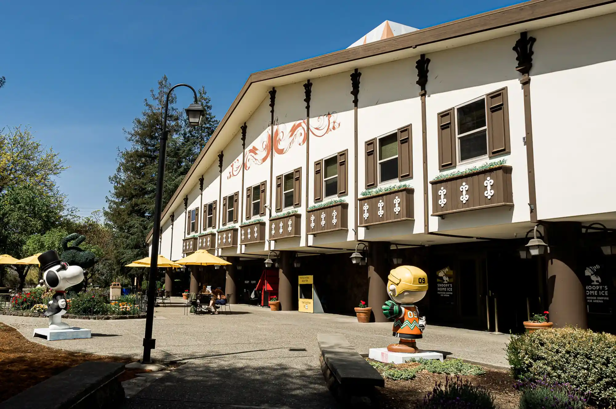 The exterior of Snoopy's Home Ice rink featuring character statues and alpine-style design.