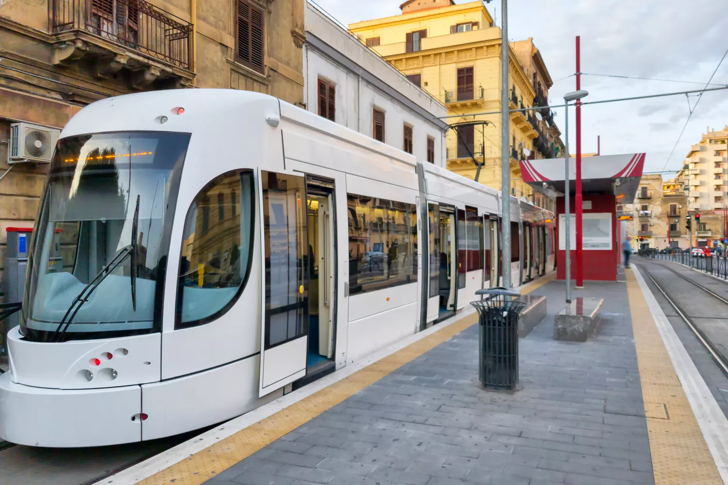 A modern white urban tram operating on the streets of Palermo.