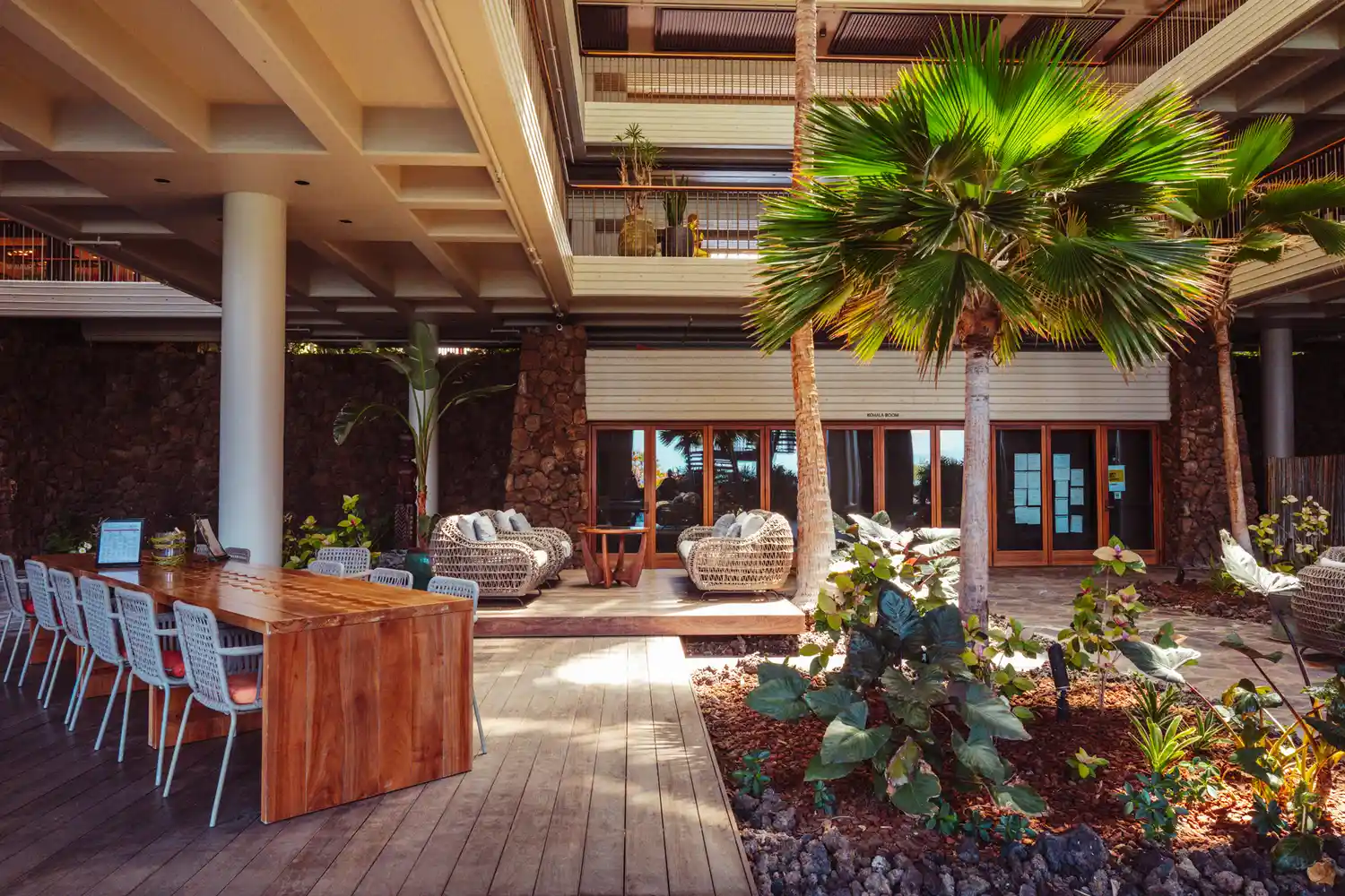 Outdoor dining area at Mauna Kea Beach Resort overlooking tropical greenery and the sea.
