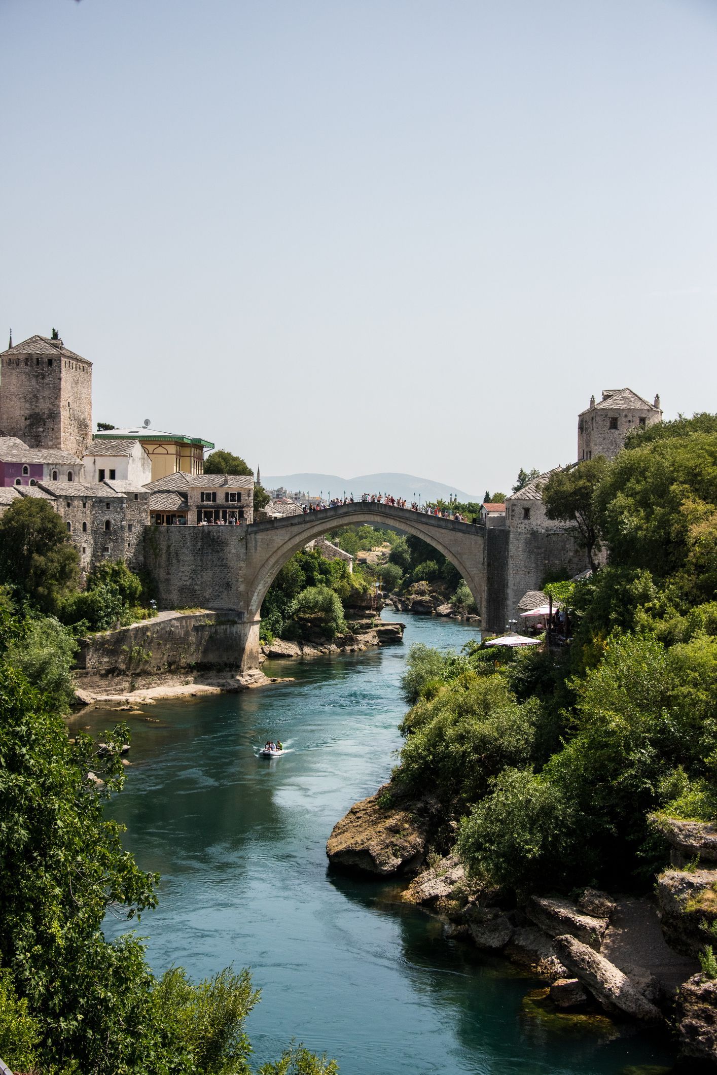 Sunlight hitting the stone buildings and the famous arched bridge in the historic center of Mostar.