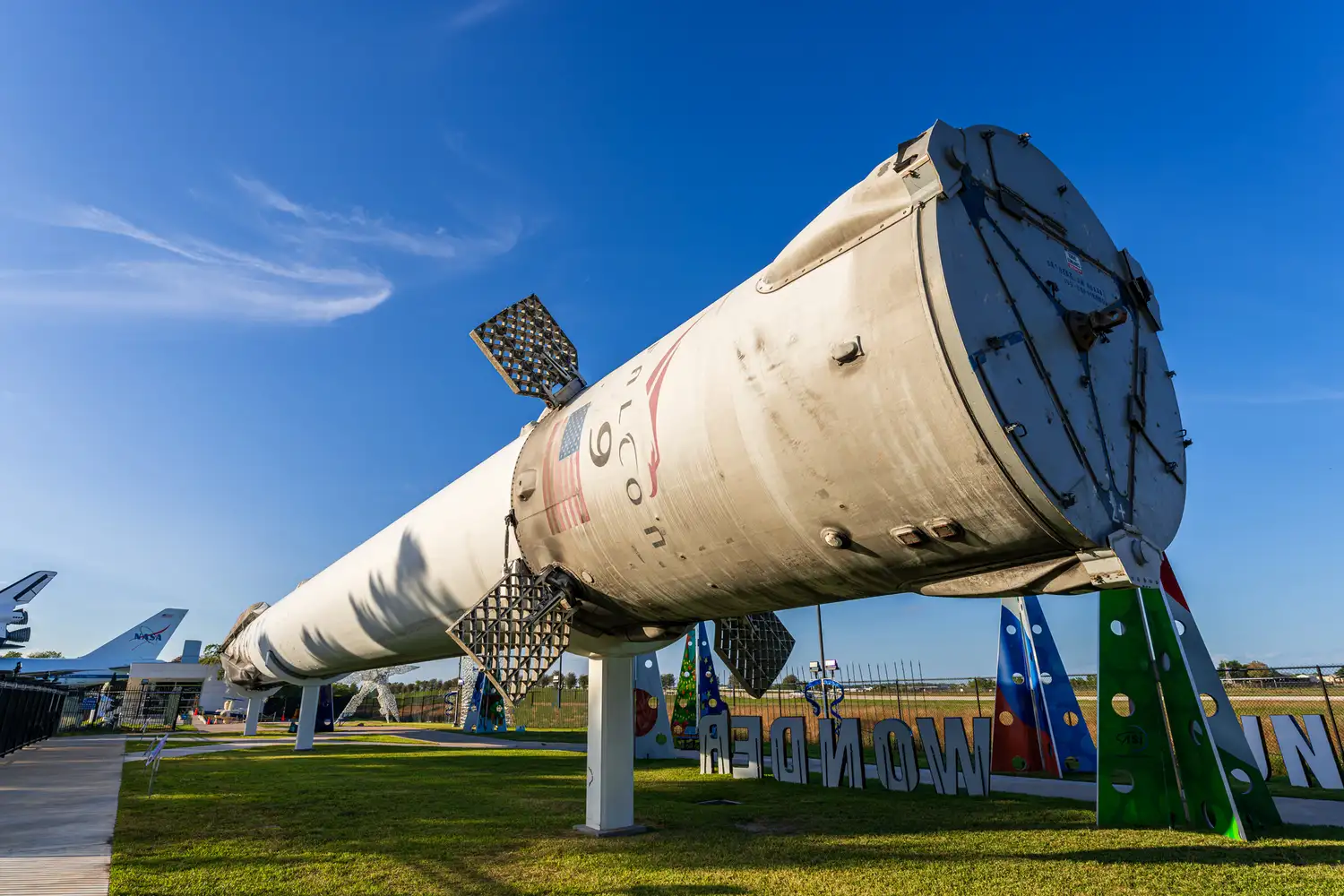 A SpaceX Falcon 9 rocket booster displayed vertically in an outdoor exhibit at Space Center Houston.