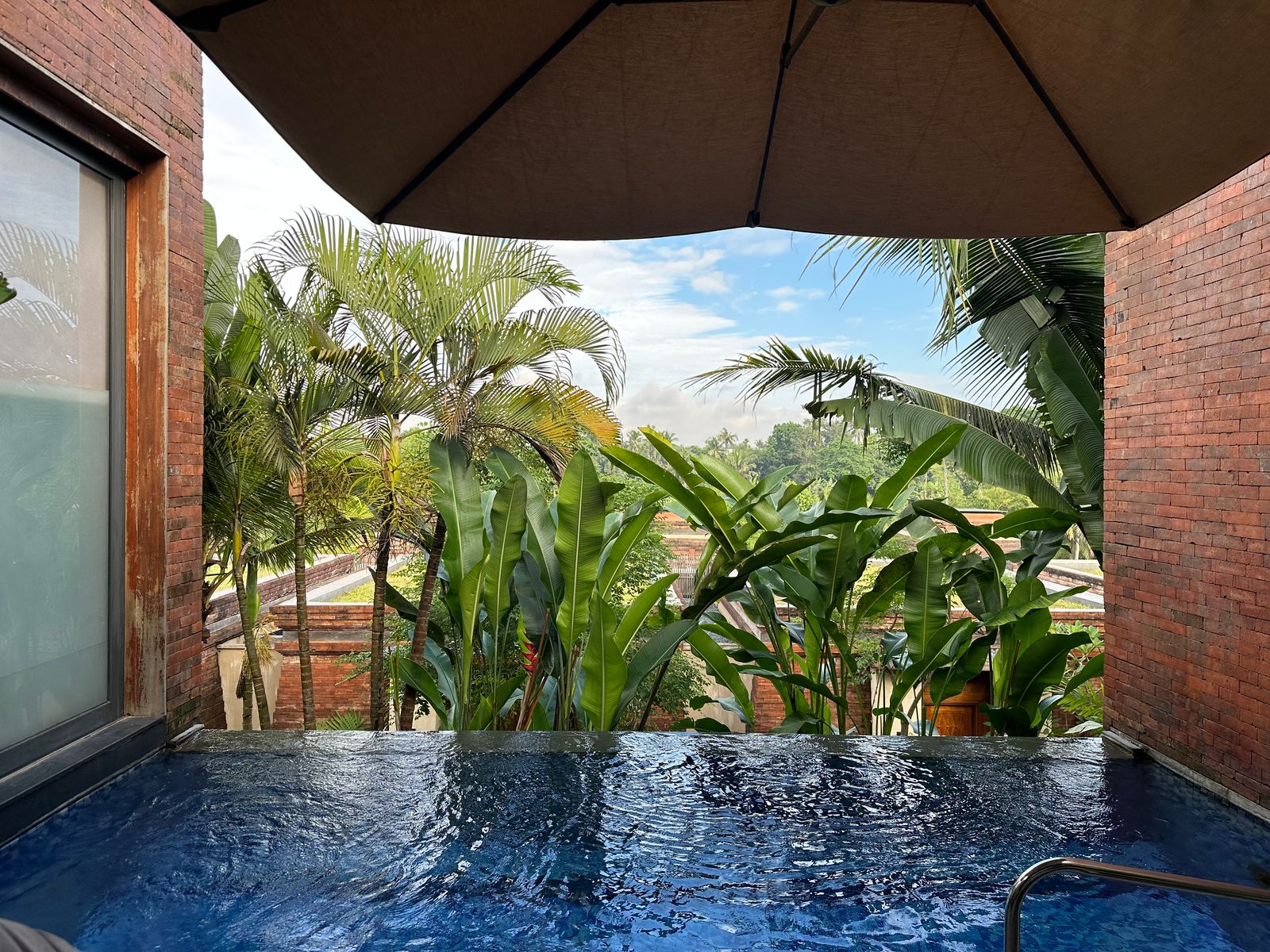 A luxury resort swimming pool surrounded by lush tropical greenery in Yogyakarta.