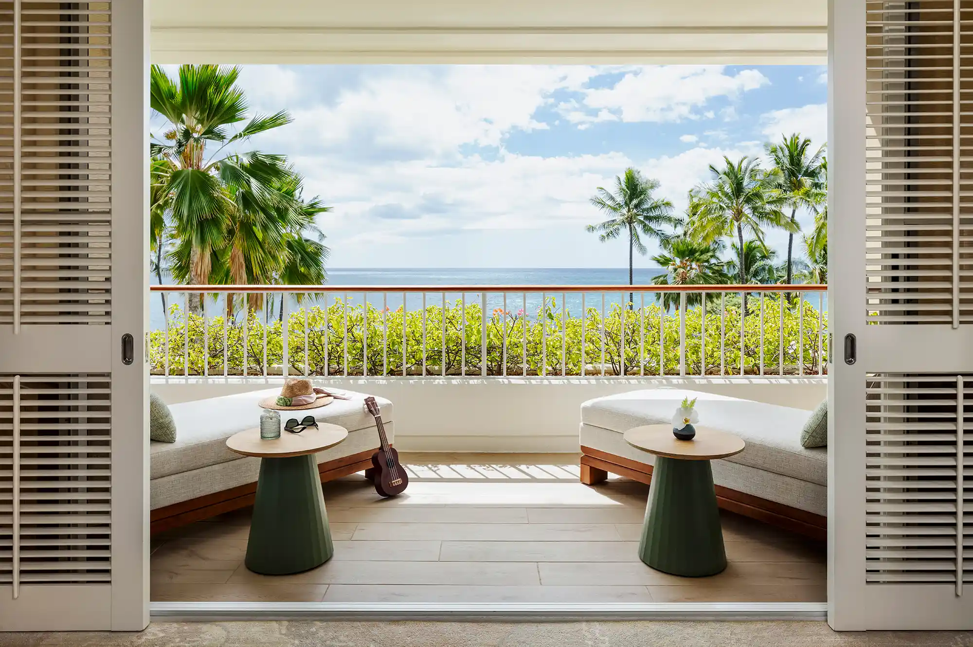 A luxurious resort terrace with tables and chairs overlooking palm trees and the ocean.