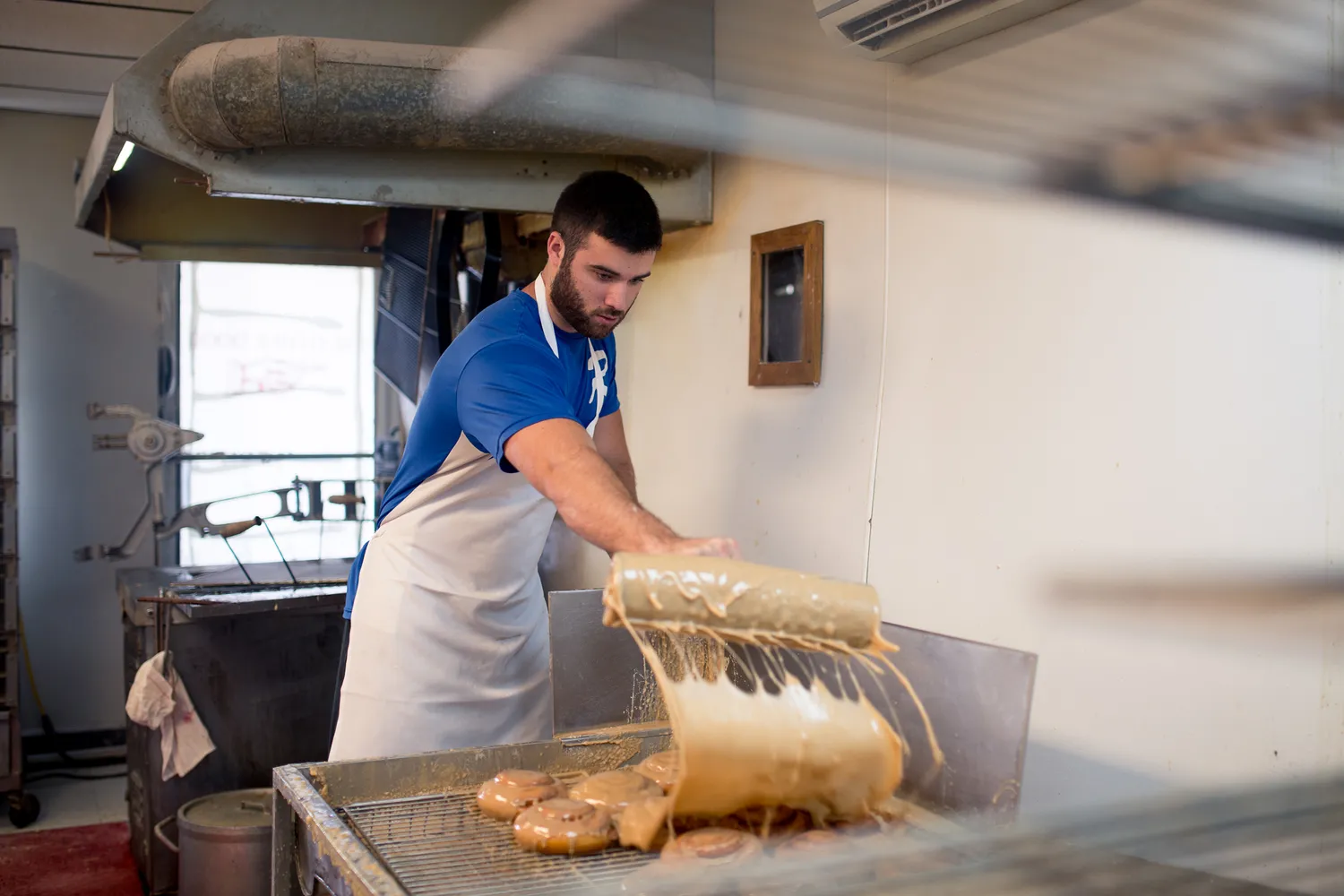 A close-up of fresh donuts being glazed at a local bakery.