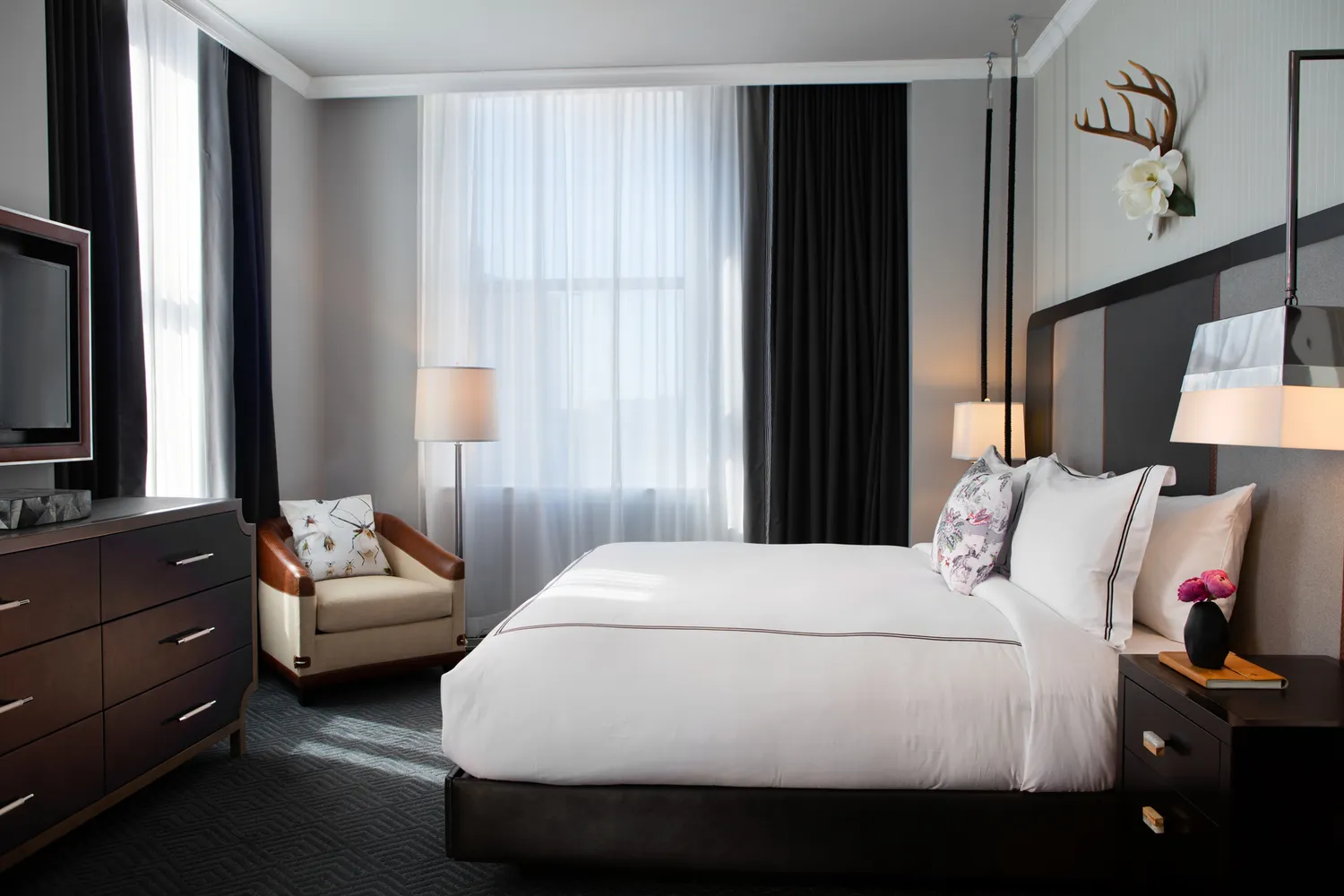 A sophisticated guest room at the Kimpton Cardinal Hotel with modern furnishings and decorative wall accents.