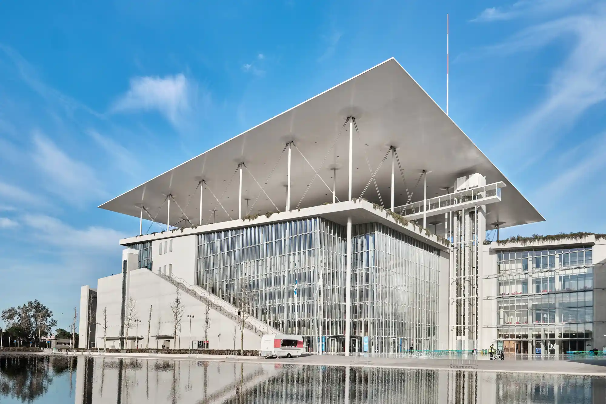The modern glass and steel architecture of the Stavros Niarchos Cultural Center under a clear sky.