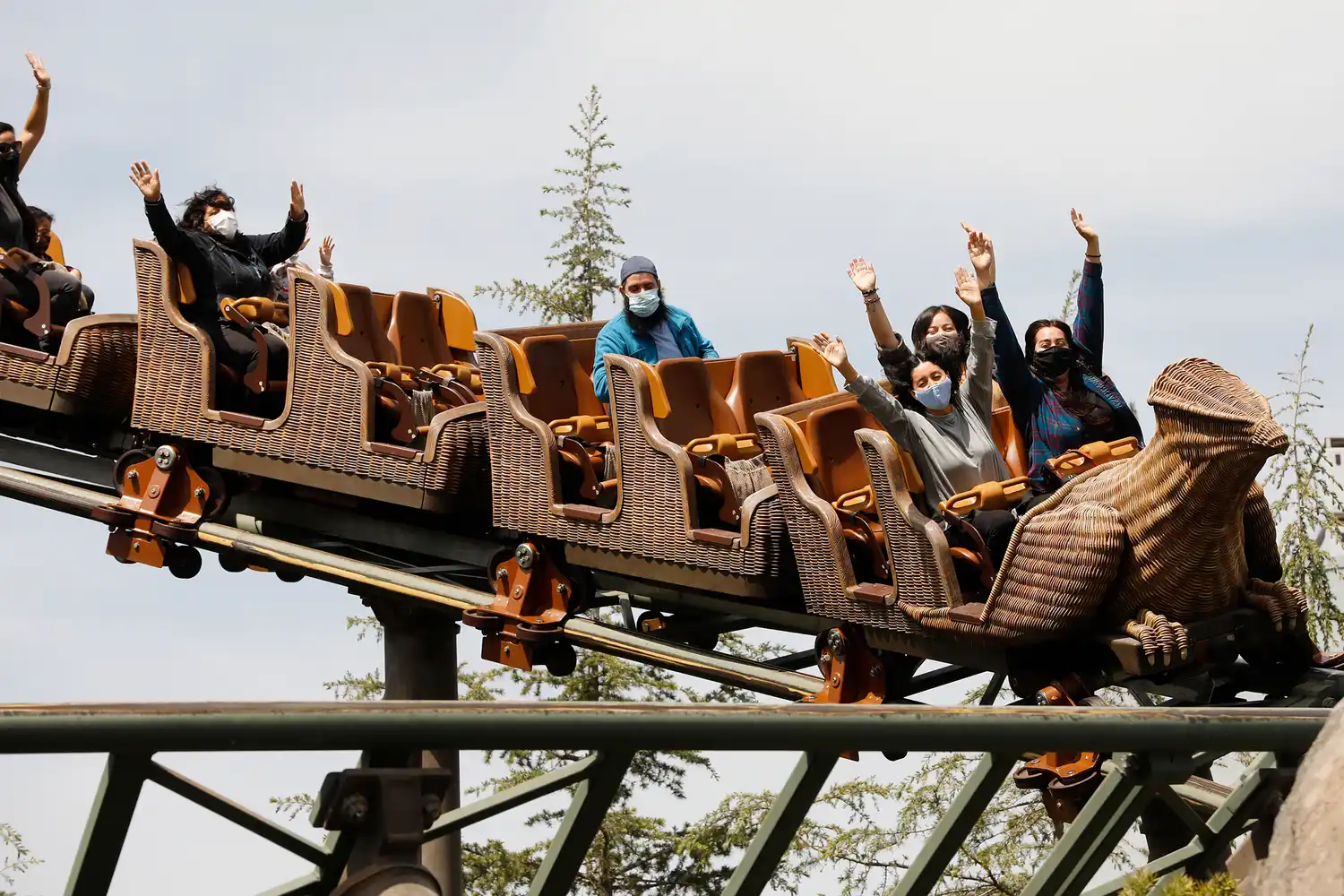 Families riding the Flight of the Hippogriff roller coaster with their hands raised.