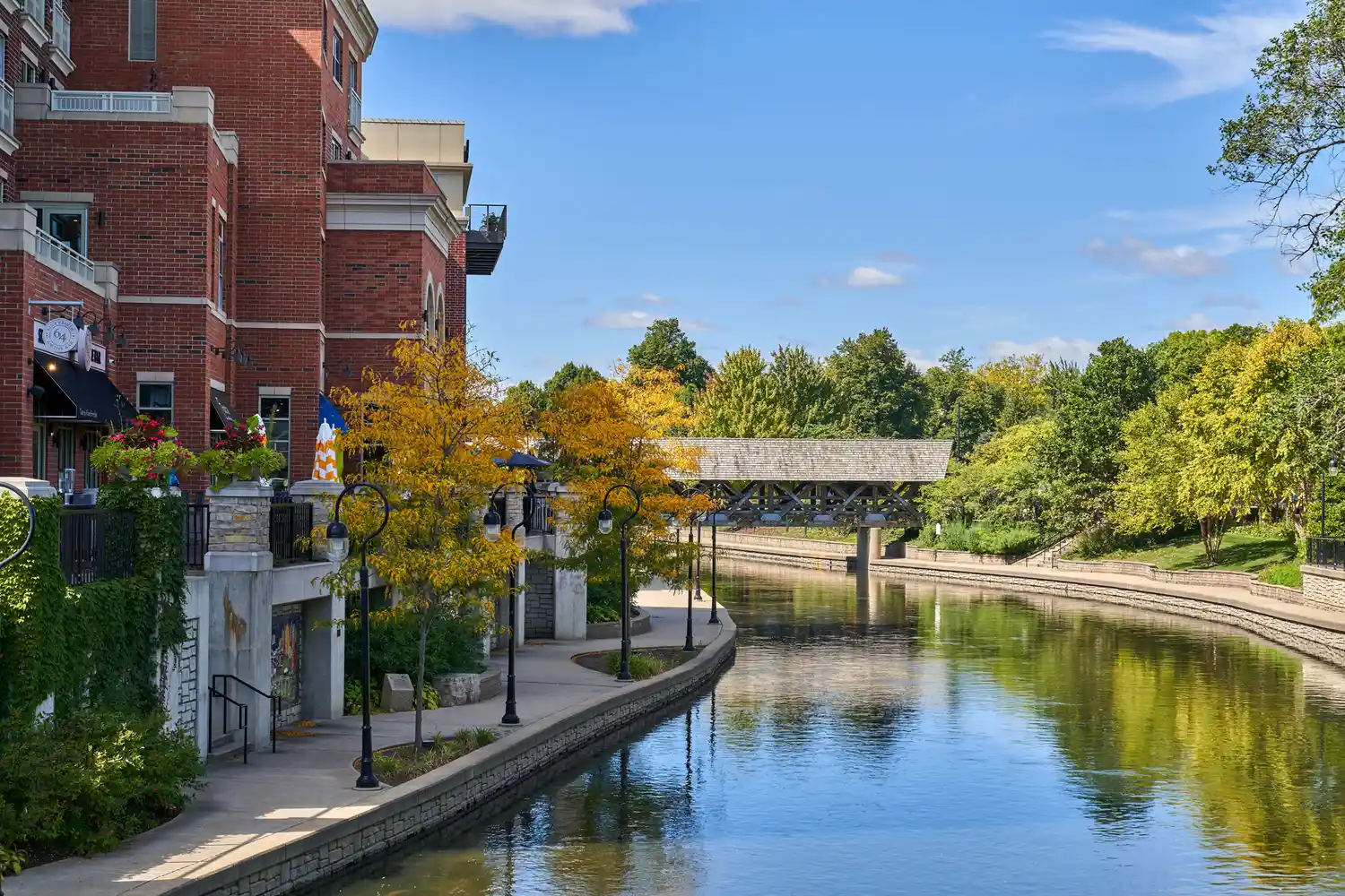 A calm riverwalk path with a covered bridge in the background.