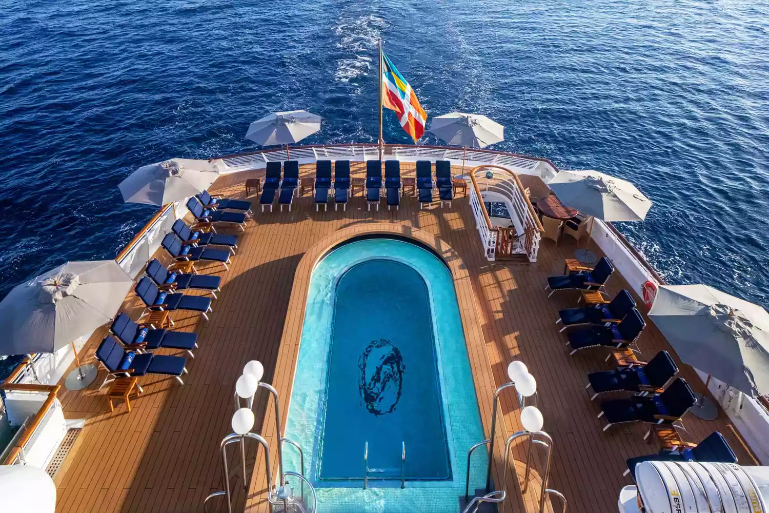 A luxurious pool deck on a SeaDream Yacht Club ship overlooking the ocean.