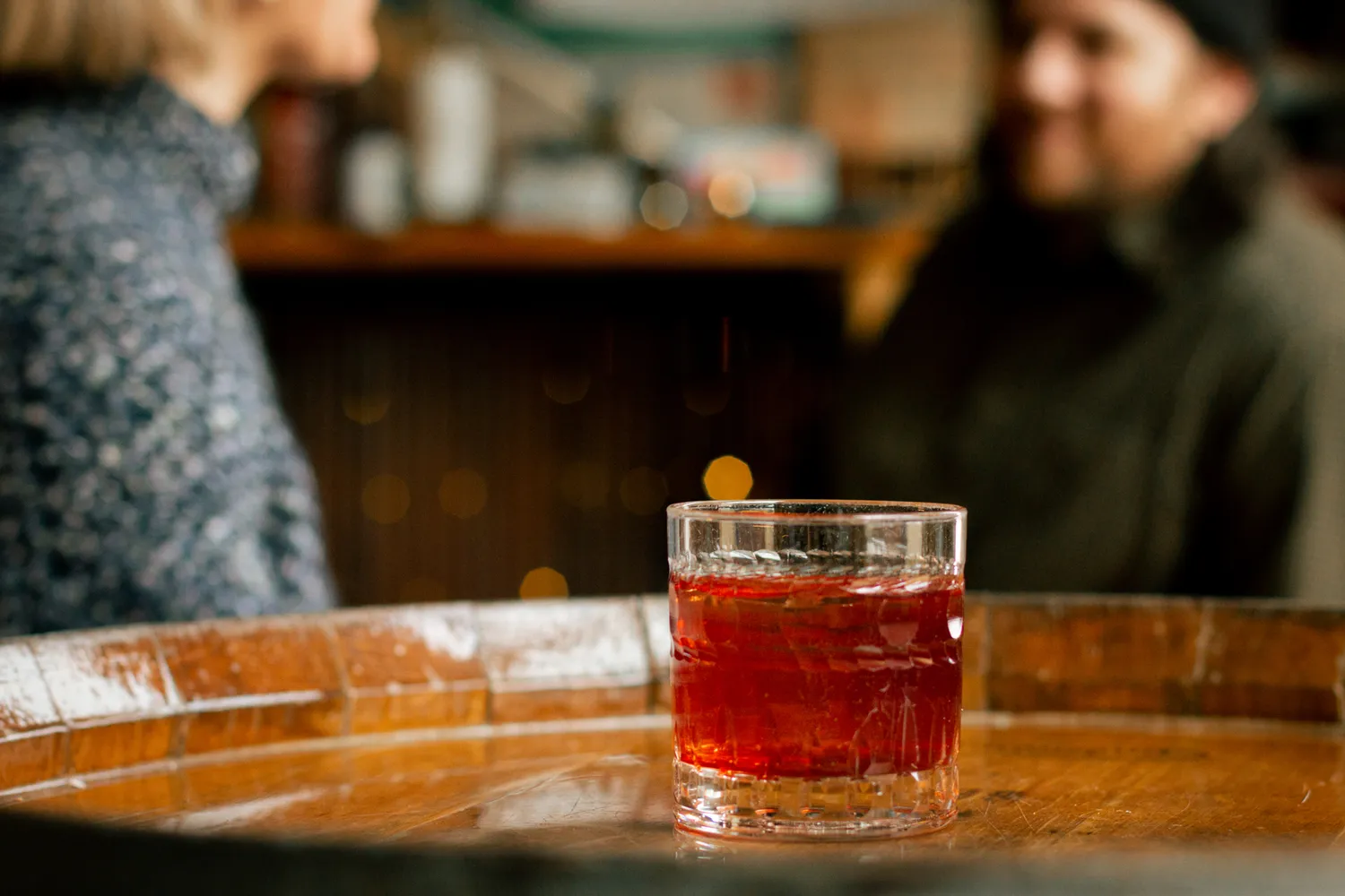 A close-up of a vibrant cocktail served on a rustic wooden table at a Duluth distillery.