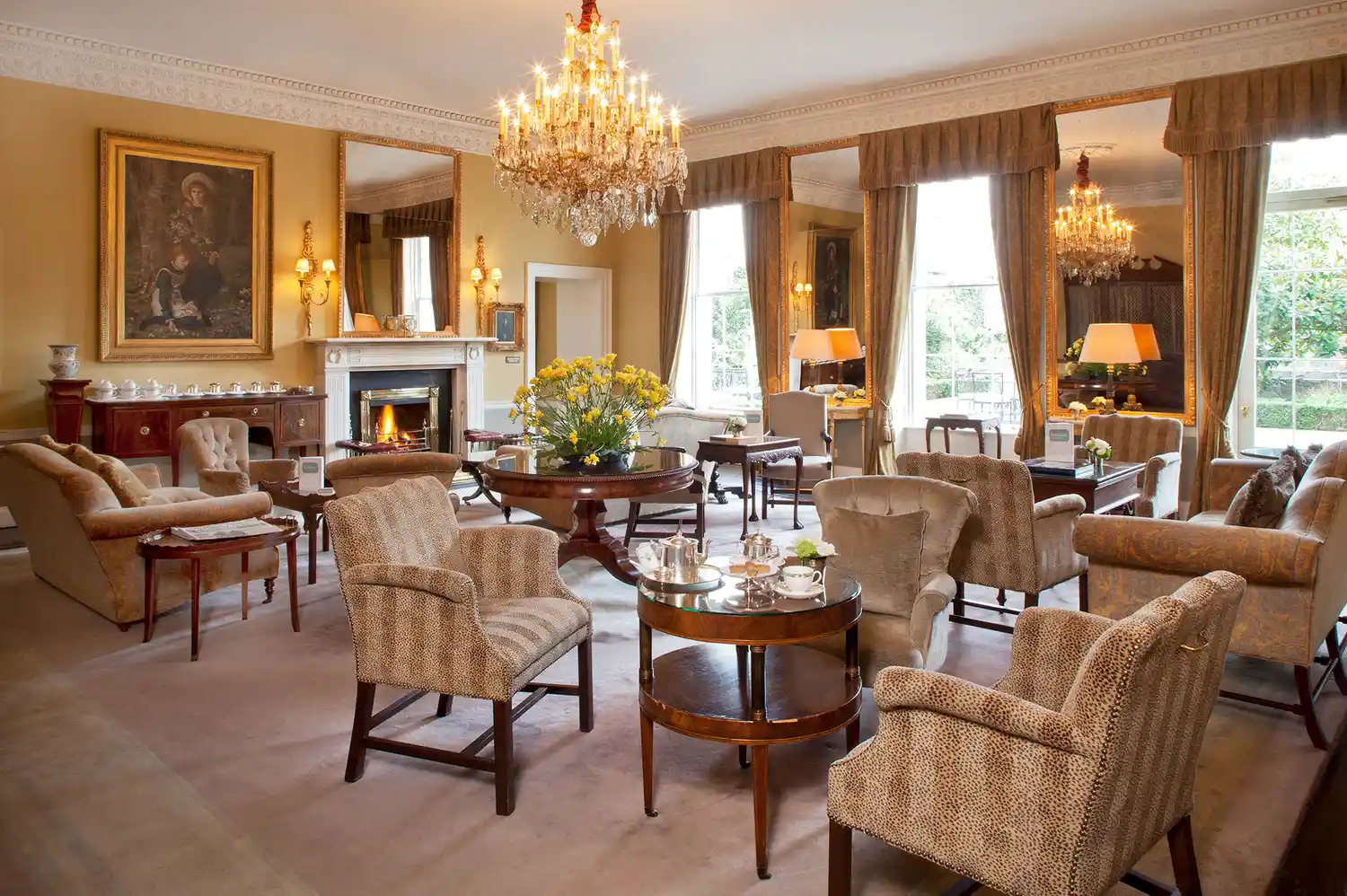 The Drawing Room at The Merrion Hotel with paintings on the walls, a fireplace, and comfortable armchairs.