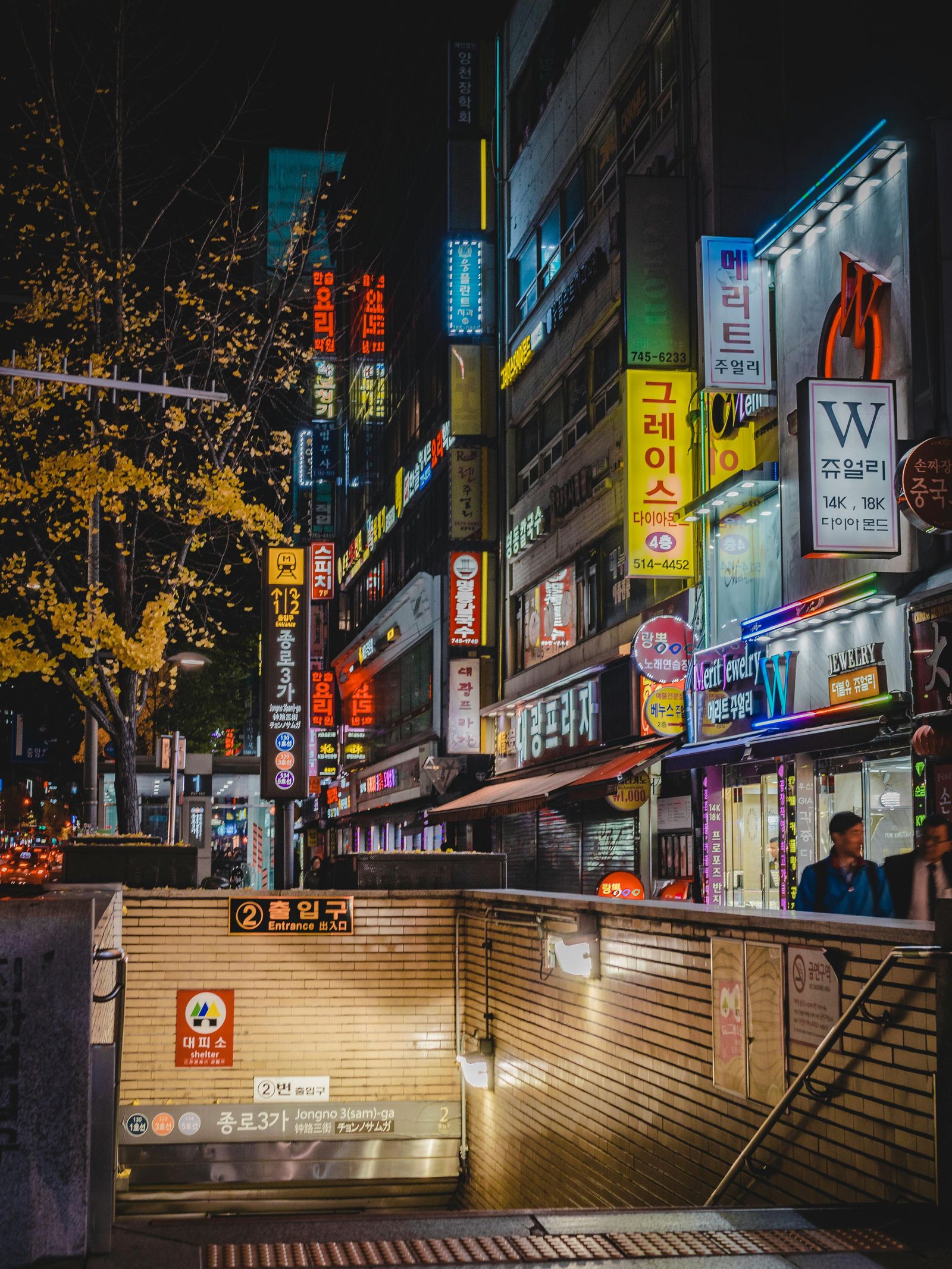 A nighttime cityscape of Seoul featuring a mix of buildings and urban life.