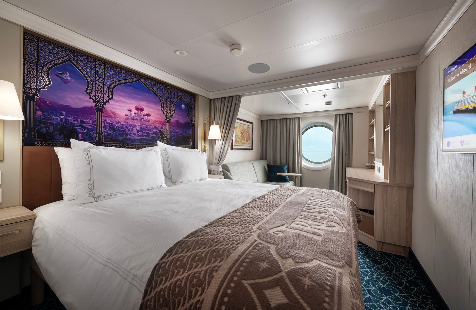 An elegant and large cruise ship suite bedroom with refined interior design and soft lighting.