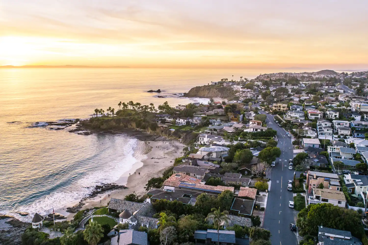 Aerial view of a coastal road in Laguna Beach during a golden sunset.