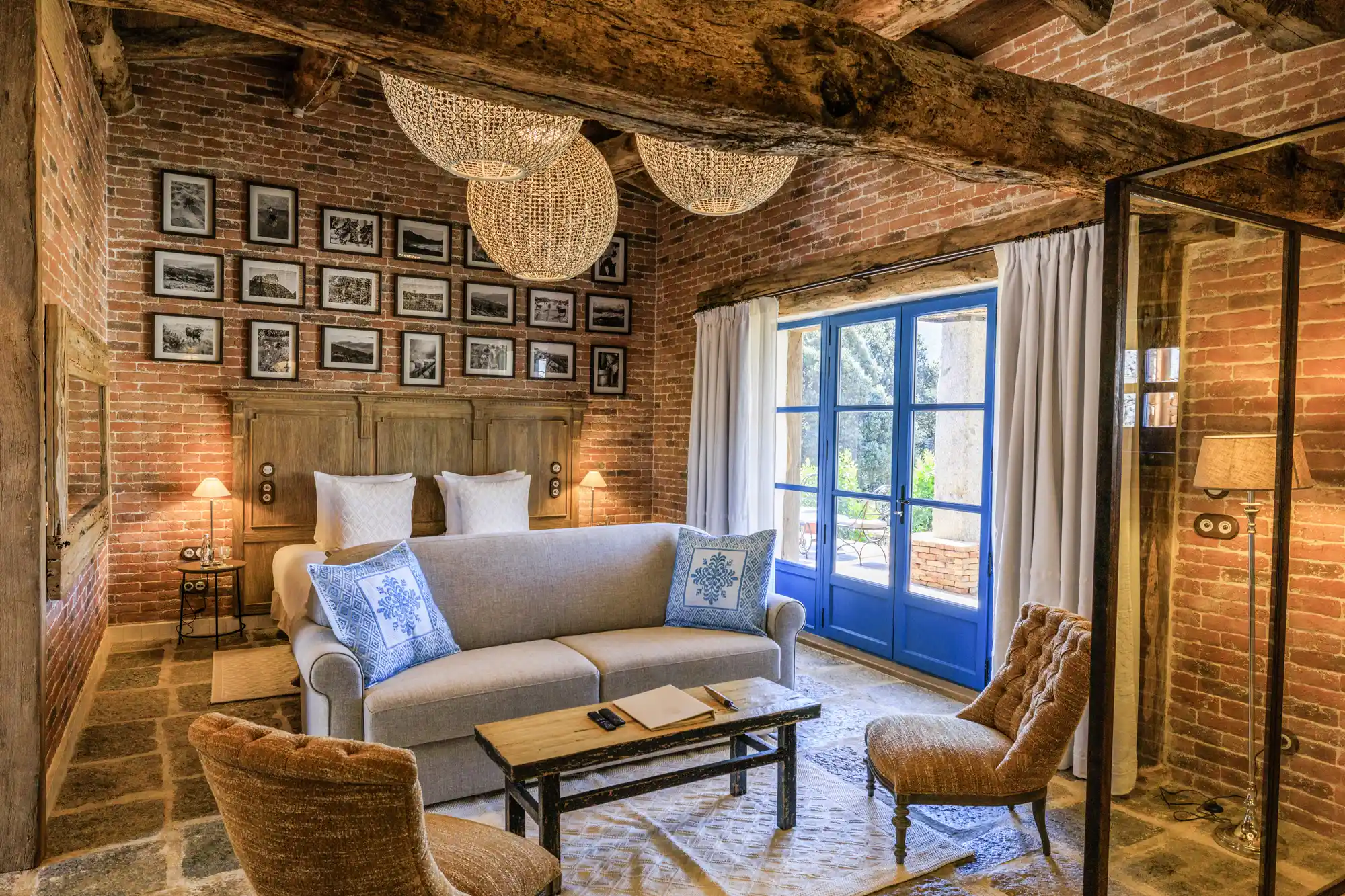 An interior seating area with exposed wooden beams and a view through French doors of the garden.