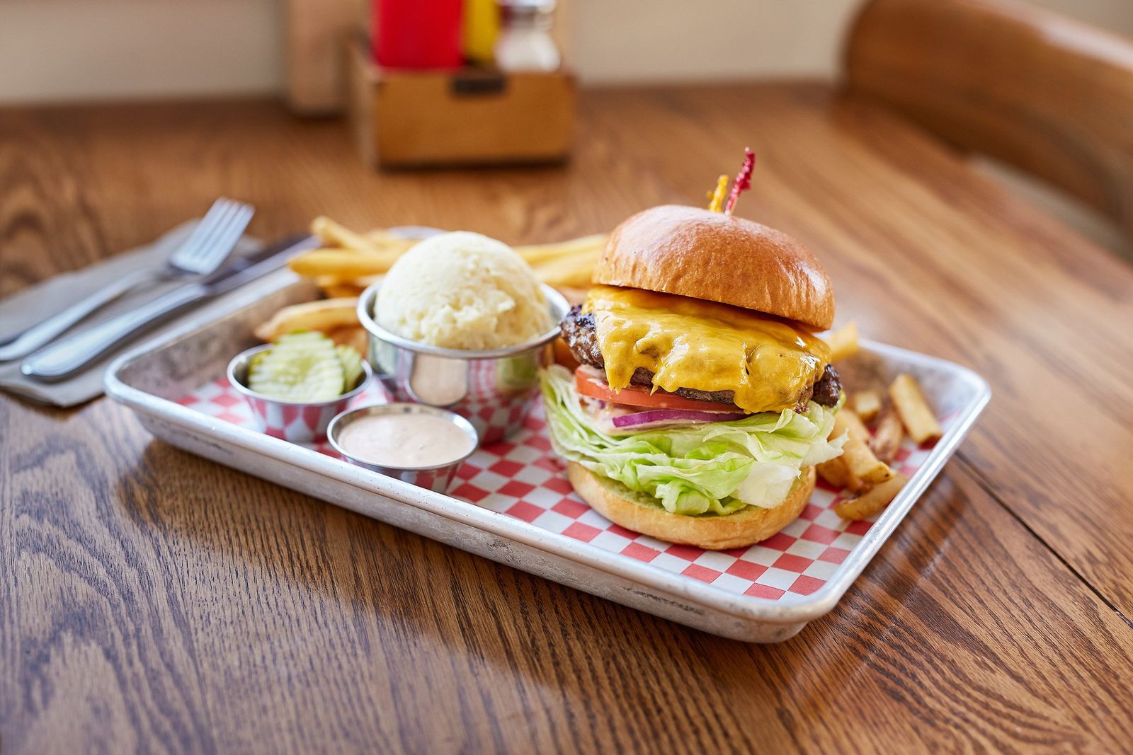 A burger served in a cardboard box alongside a milkshake and fries, typical of late-night pop-up culture.