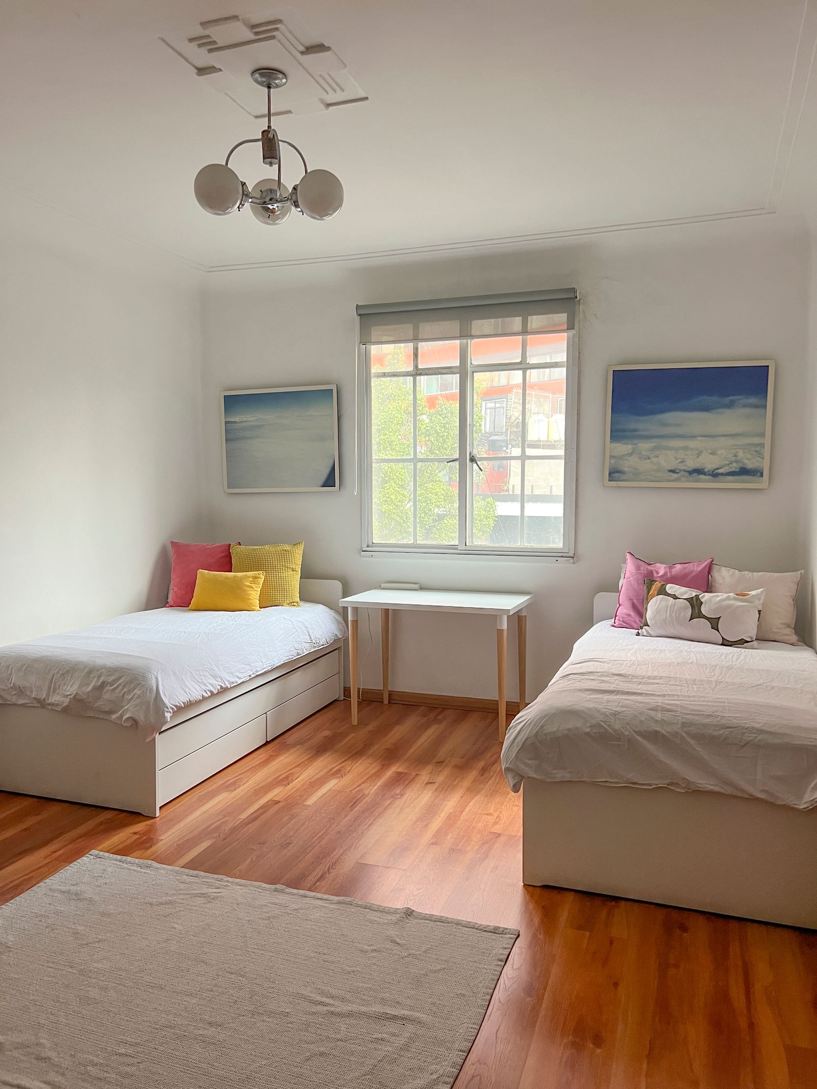 A cozy bedroom in a Roma Mexico City Airbnb with a desk, art painting, and comfortable cushions.