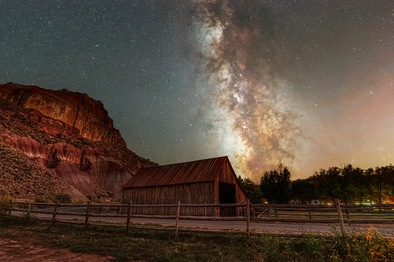 The Milky Way galaxy visible in a dark sky above the historic wooden Fruita Barn in Capitol Reef.