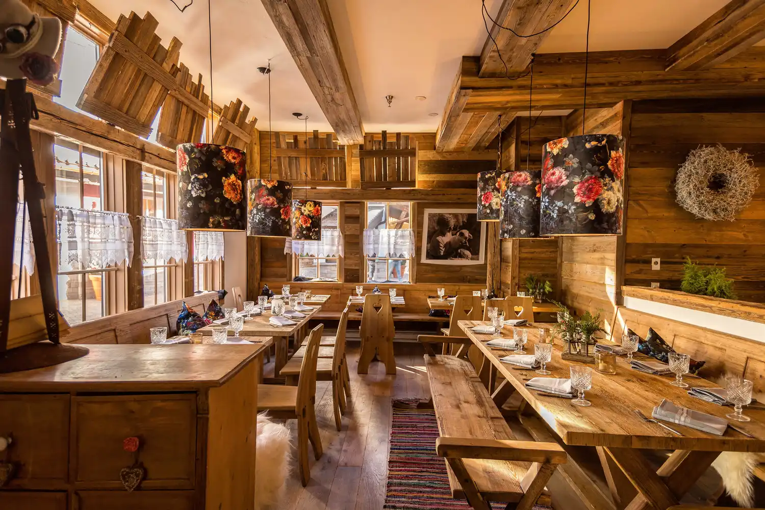 The rustic, wood-paneled interior of a Bavarian-style restaurant with floral lampshades.
