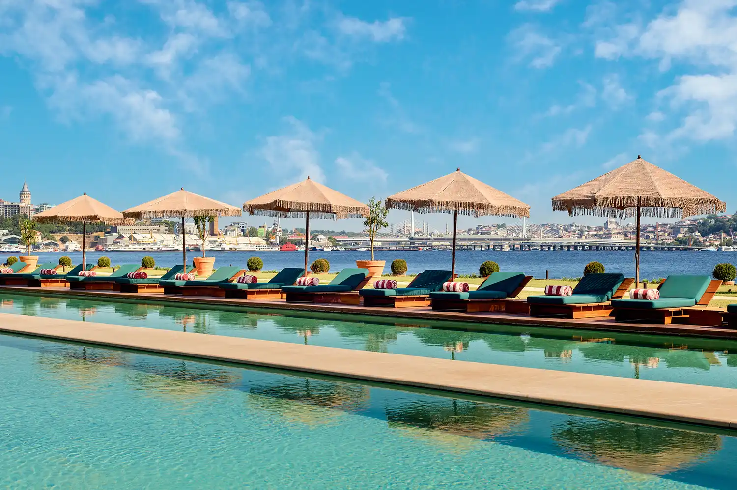 The Aliée Swim Club with yellow parasols and sun loungers facing the Golden Horn.