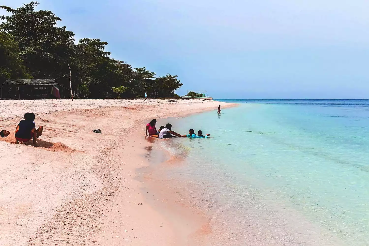Visitors on pink-tinged coralline sand created by red organ pipe coral erosion on Great Santa Cruz Island.