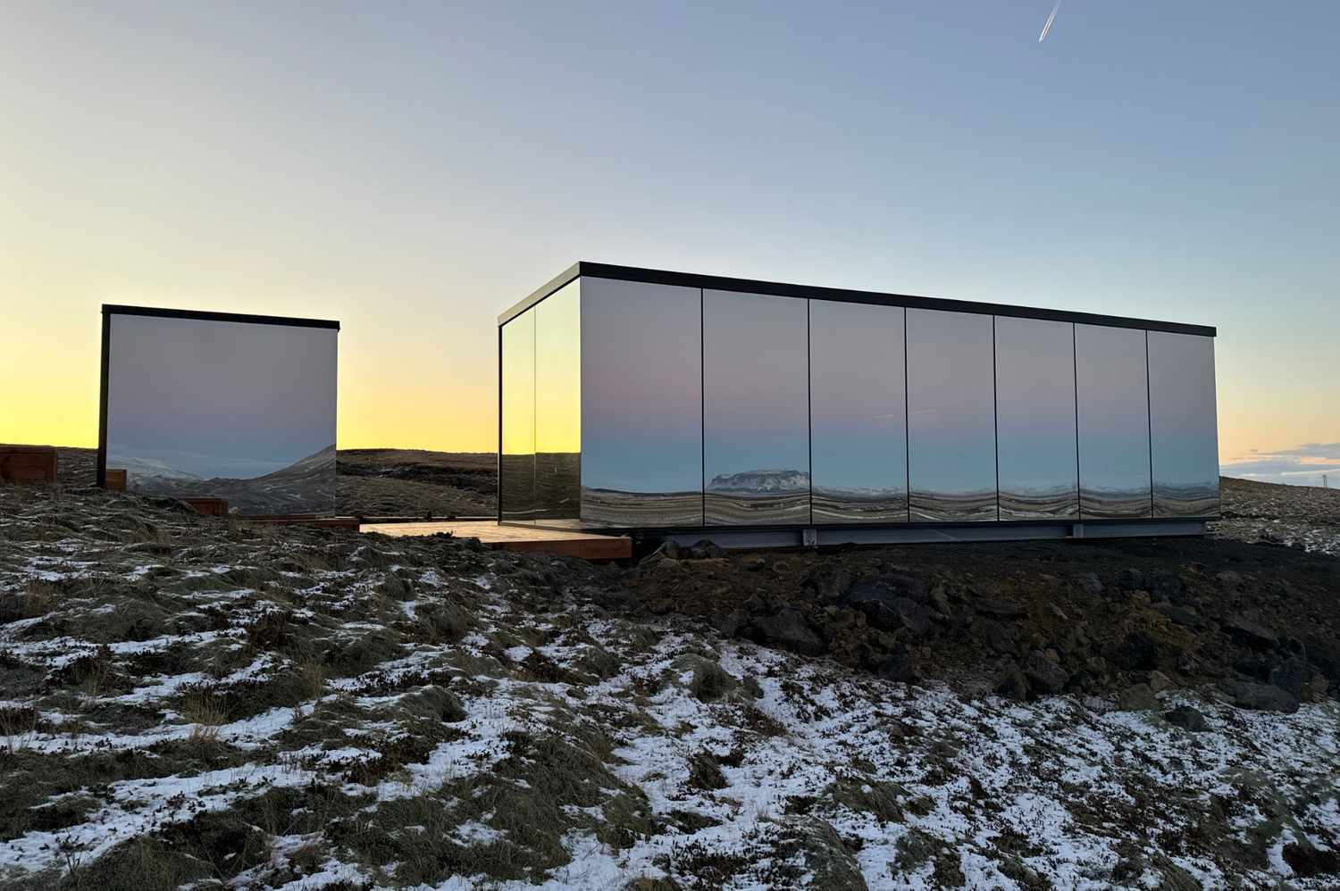 Wide shot of the ÖÖD Hekla Horizon mirror cabins in the remote Iceland wilderness.