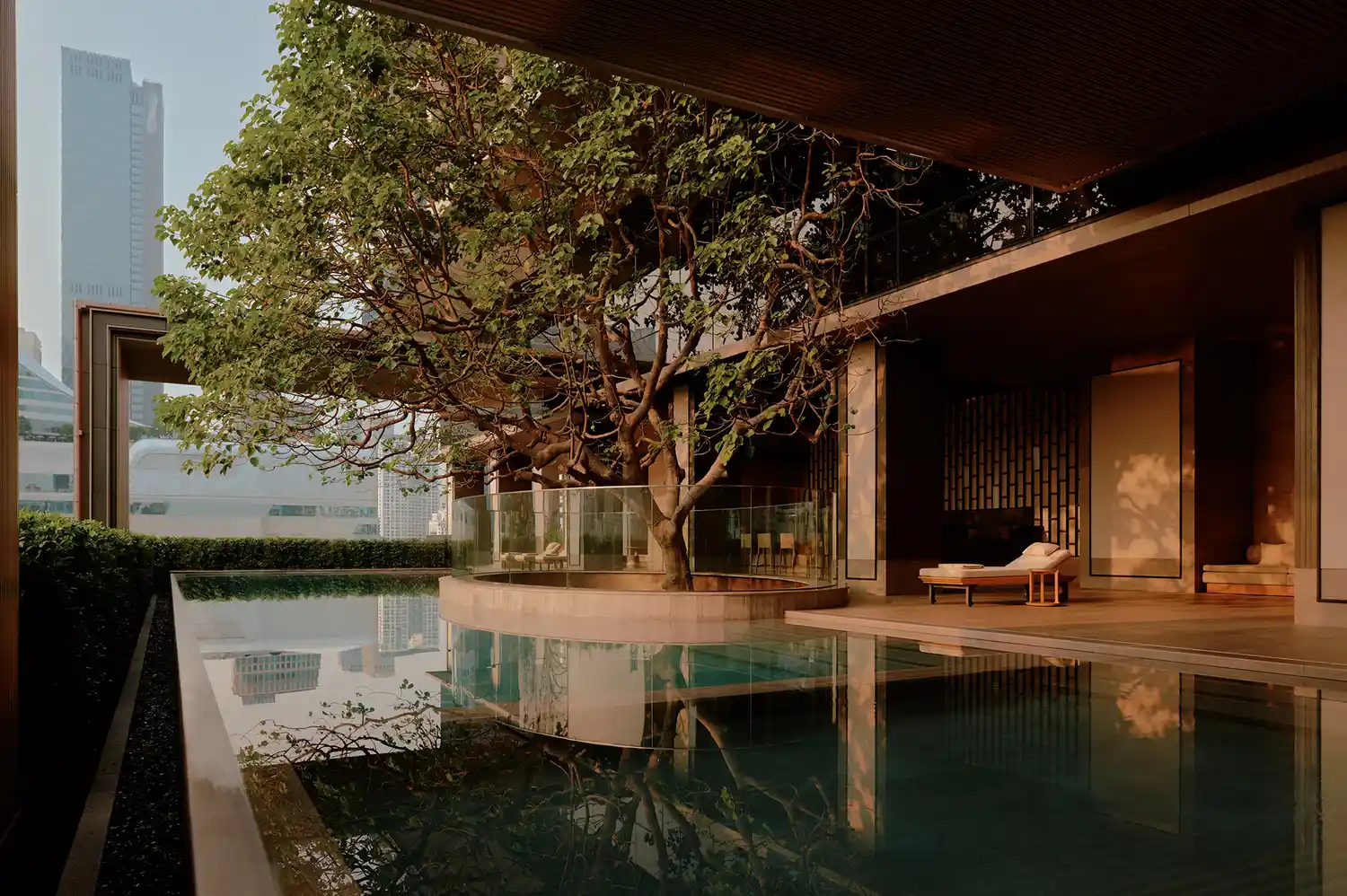 A luxury spa pool at Aman Nai Lert Bangkok overlooking the city skyline.