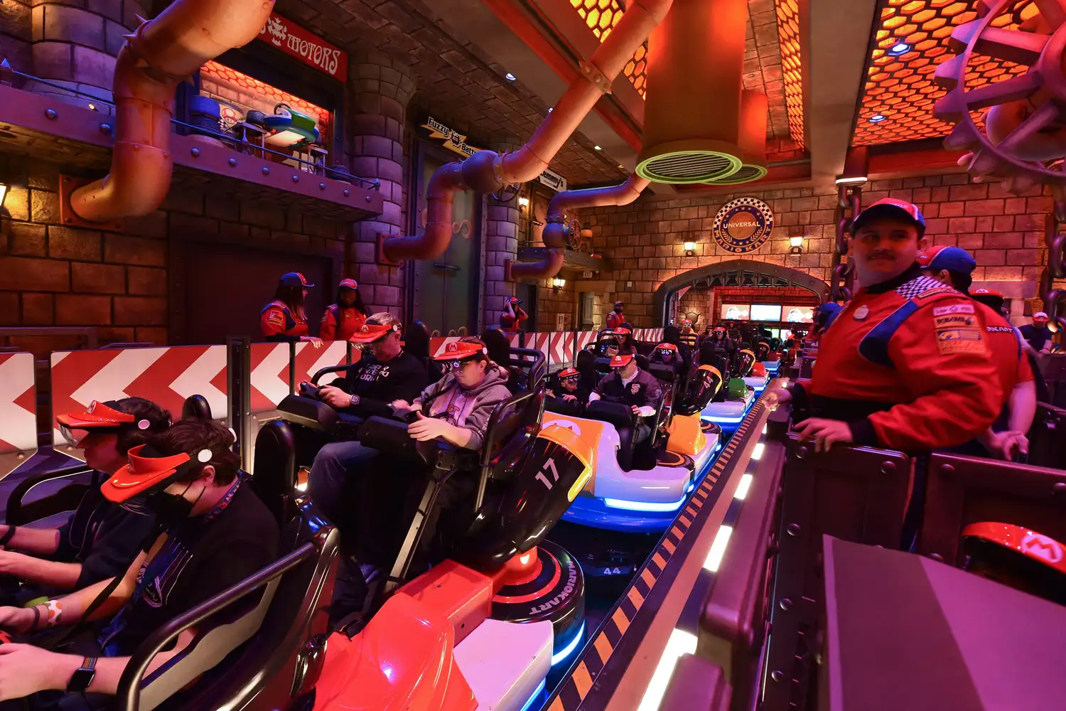 Guests seated in Mario Kart themed ride vehicles wearing AR headsets.
