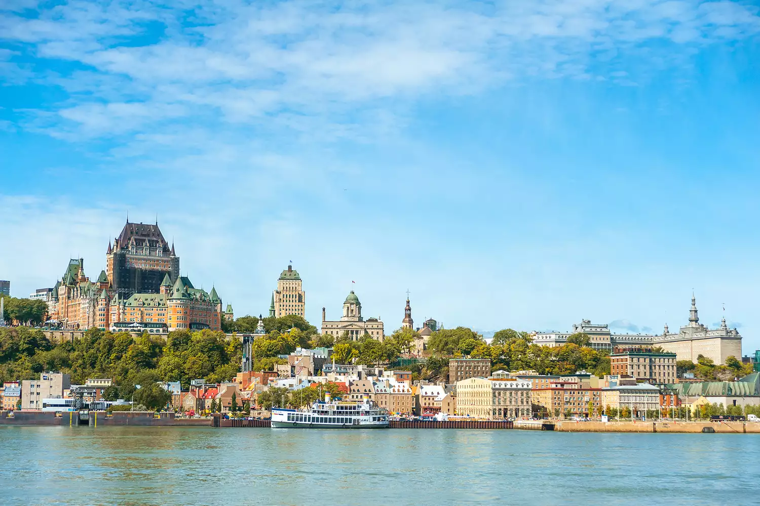 The Fairmont Le Château Frontenac overlooking the Saint Lawrence River under a clear sky in Quebec City.
