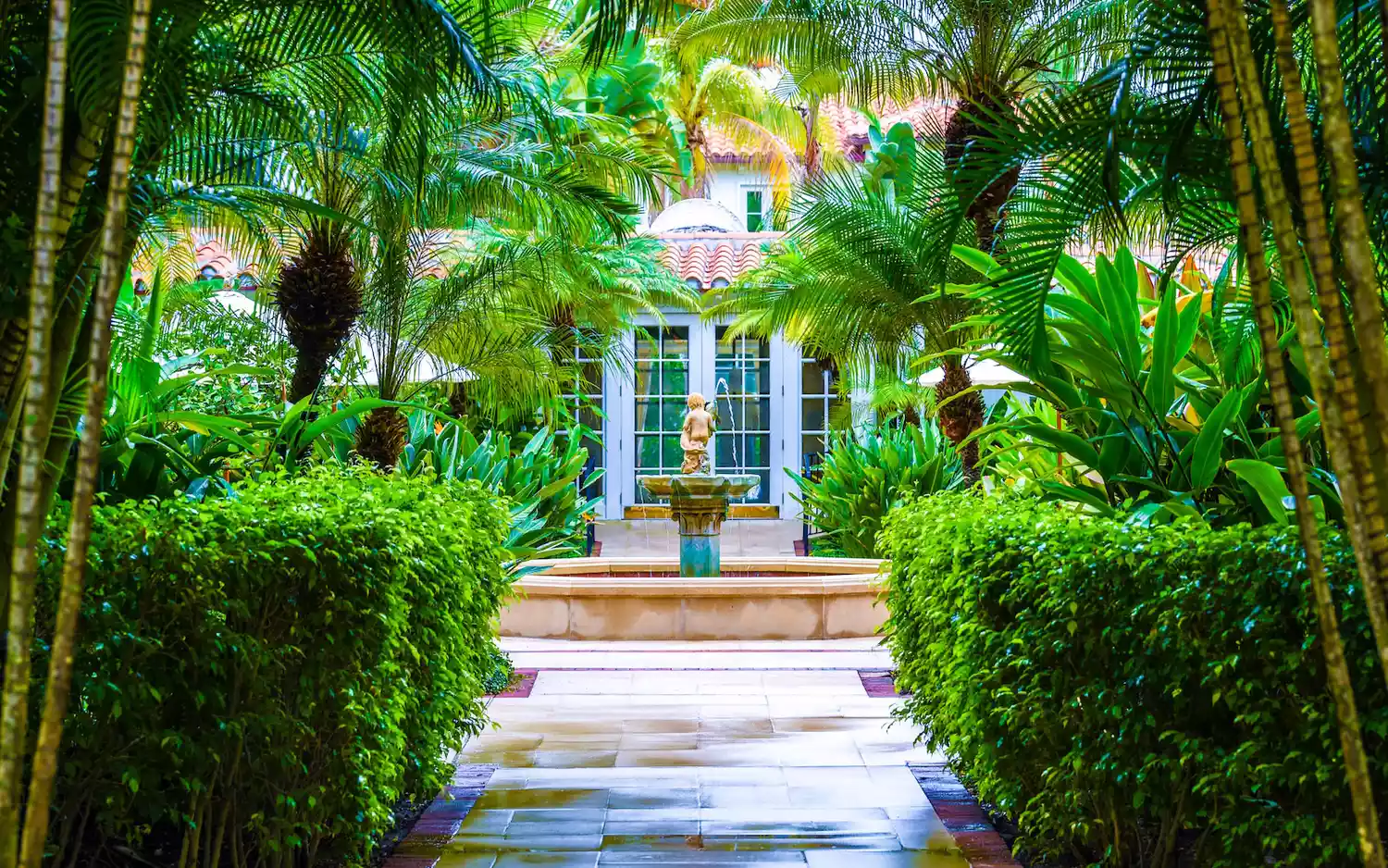 A lush, manicured tropical courtyard at the Brazilian Court Hotel.
