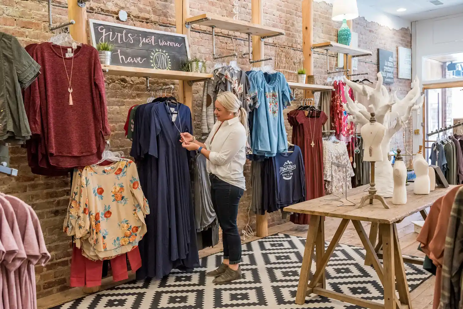 A woman browsing clothes and home decor inside a brightly lit boutique in downtown Sylva.
