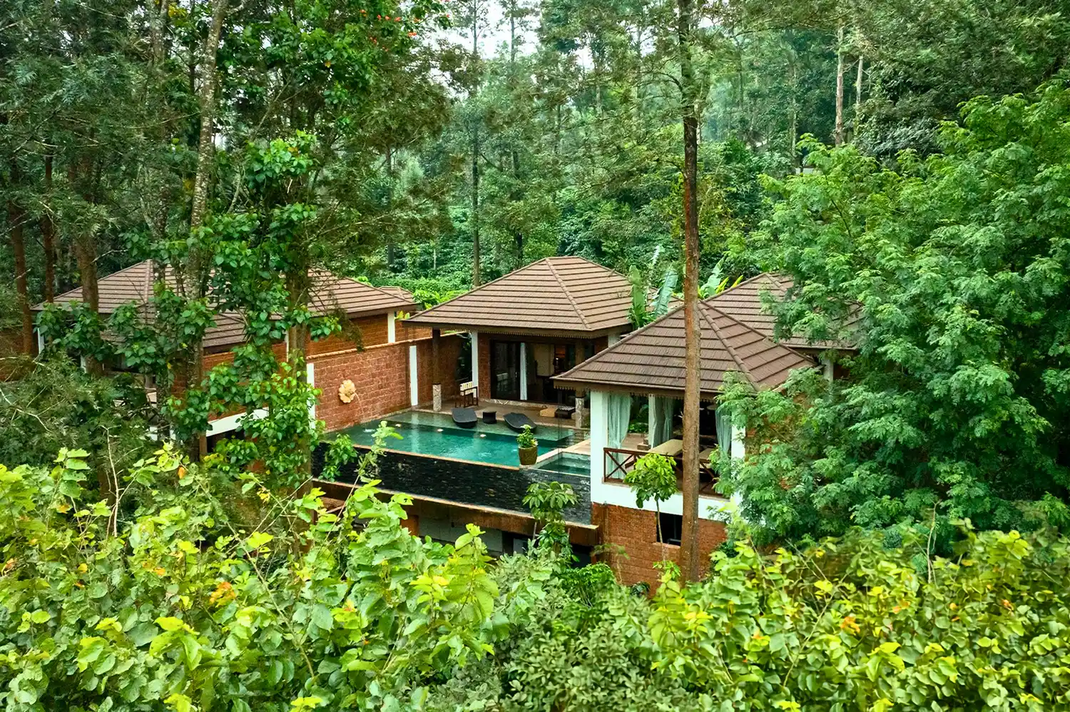 Private luxury villa at The Leela Coorg featuring a private plunge pool and dark wood architecture surrounded by trees.