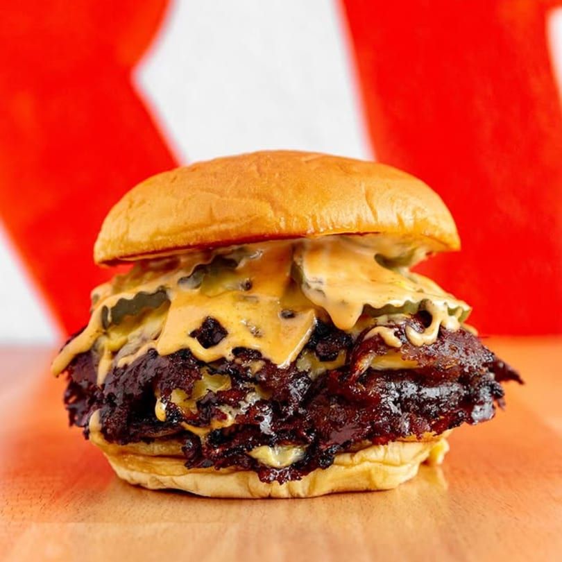 Close-up of a smash burger with thin, crispy beef edges and melted cheese on a soft bun.