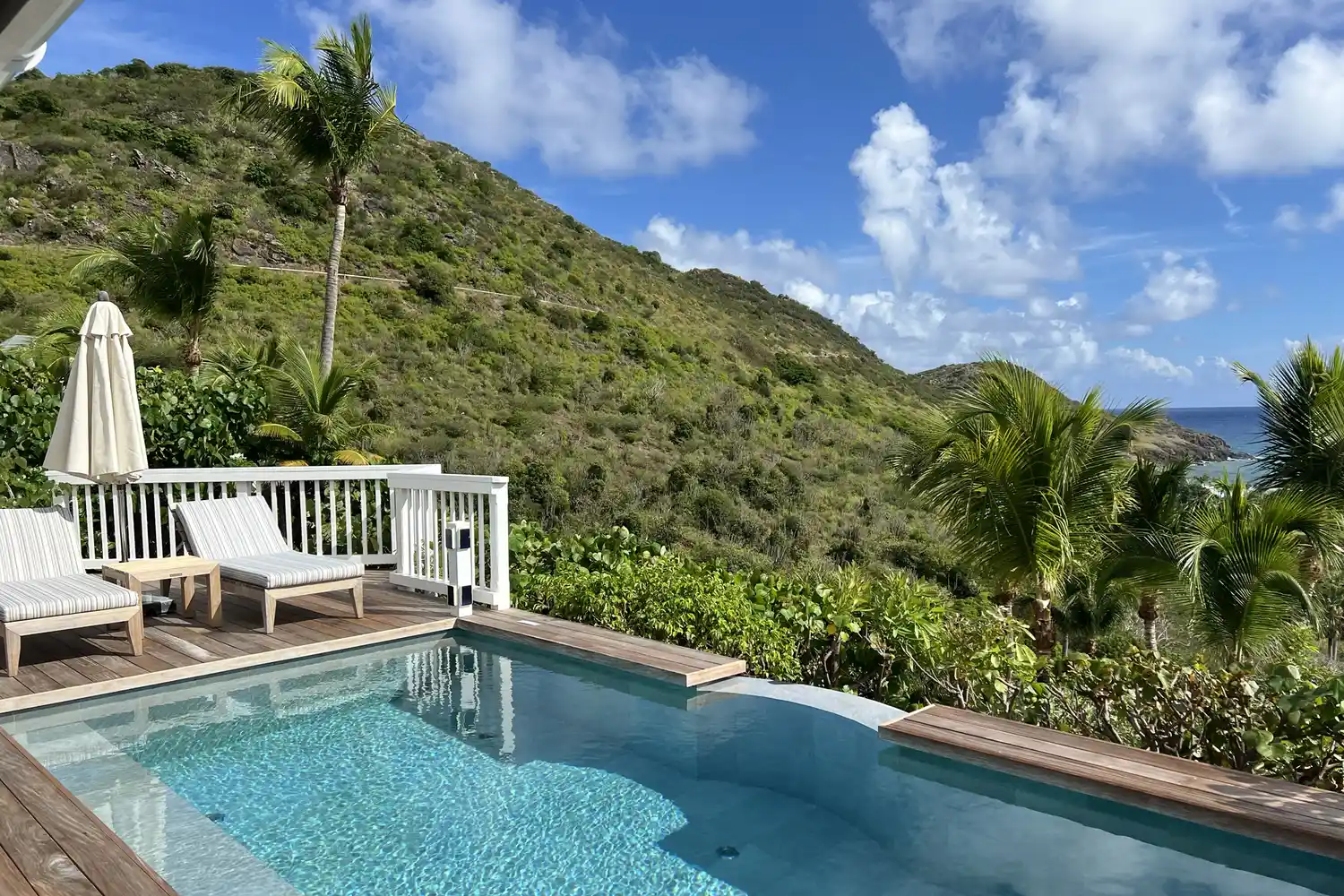 A private infinity pool at Le Toiny on a wooden deck overlooking green hills and the turquoise ocean.