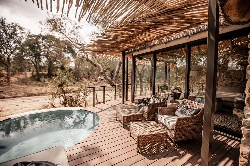 A luxury safari suite featuring a private plunge pool overlooking a dry river bed in the African savanna.