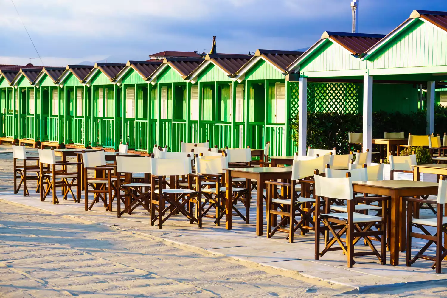 Symmetrical rows of private beach cabins at sunset in the luxury resort town of Forte dei Marmi.