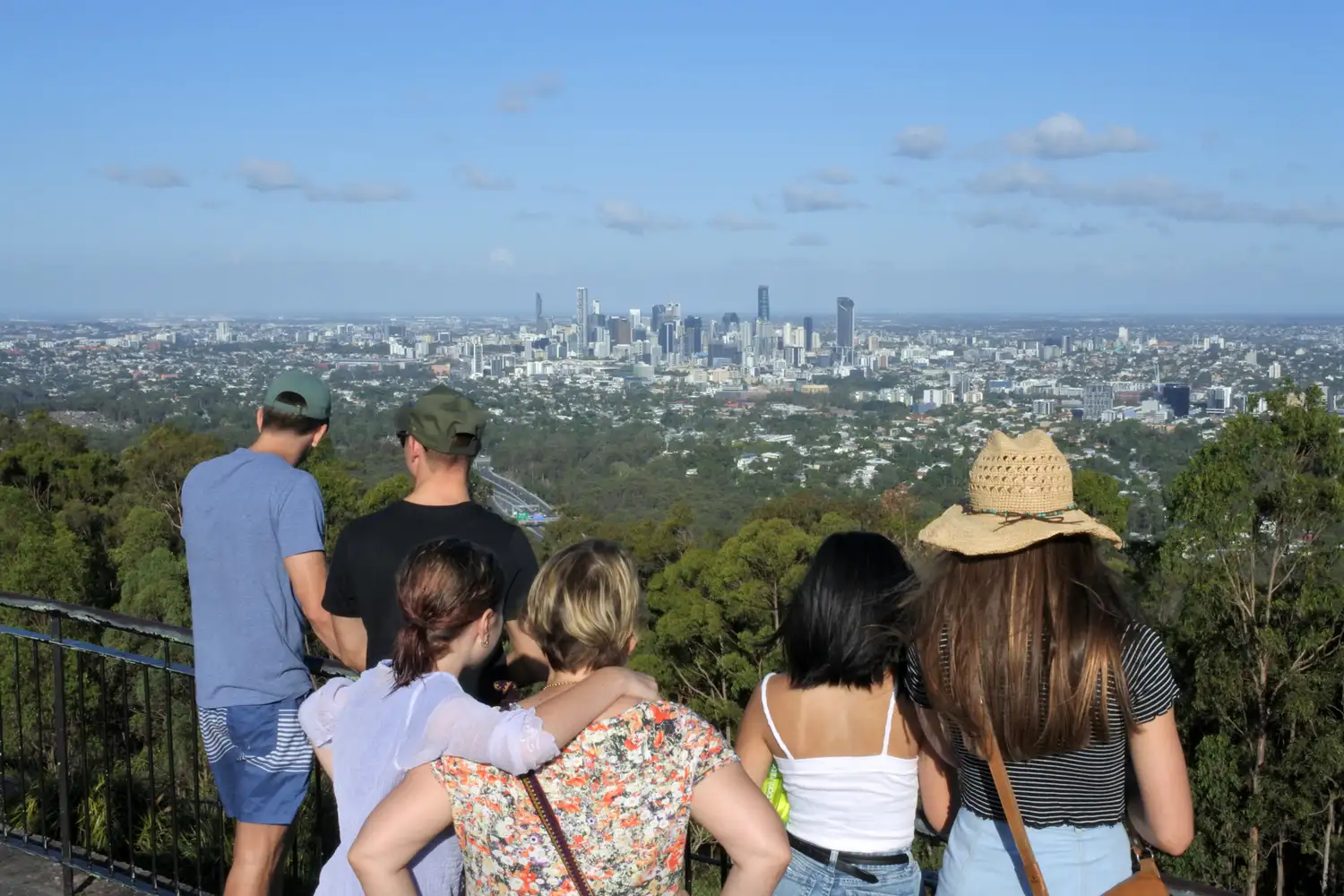 A group of people looking out at the Brisbane CBD and winding river from a high vantage point.