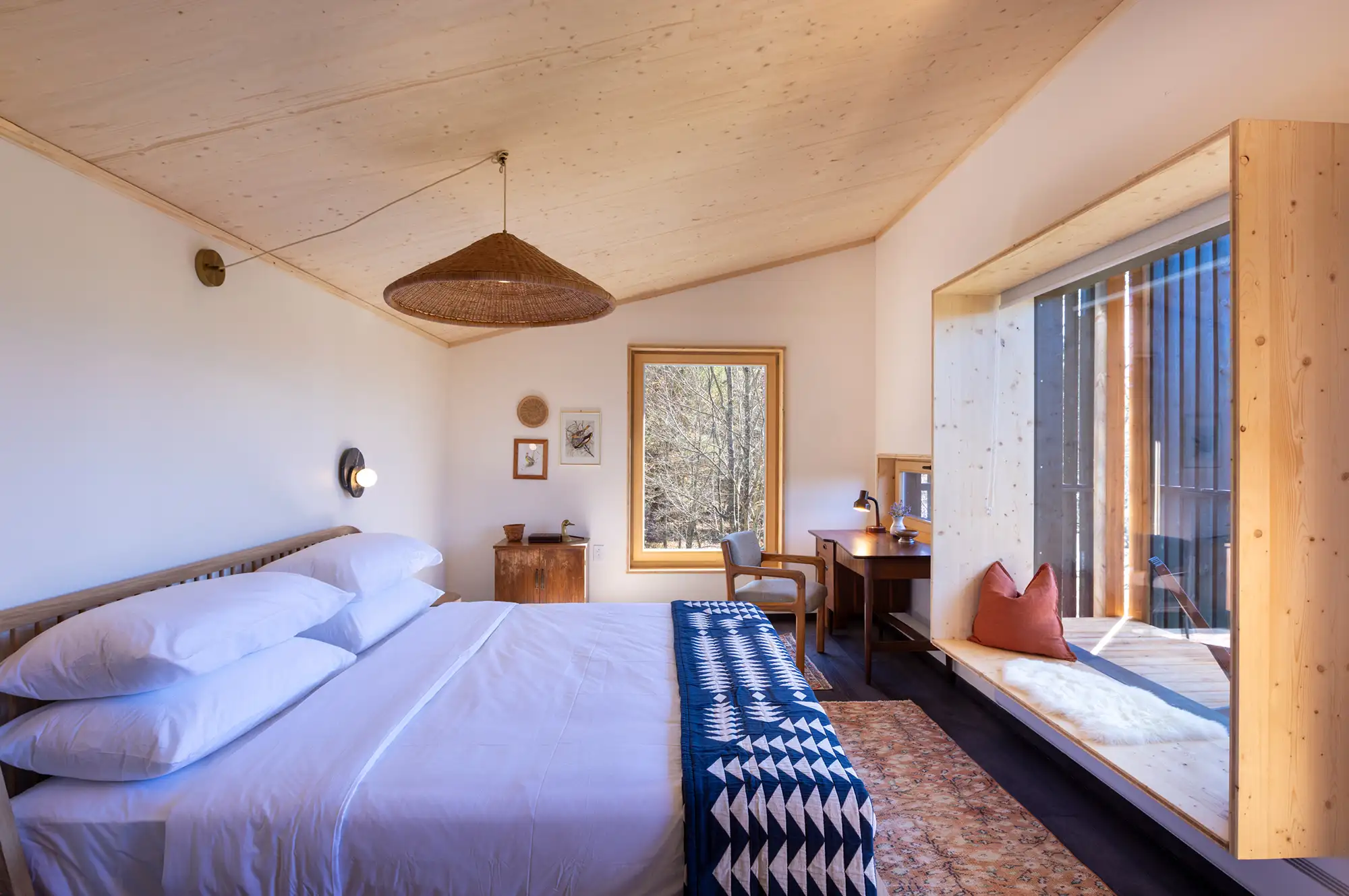 Interior of a Mountain Studio Suite with wooden ceilings, a plush bed, and minimalist furniture.