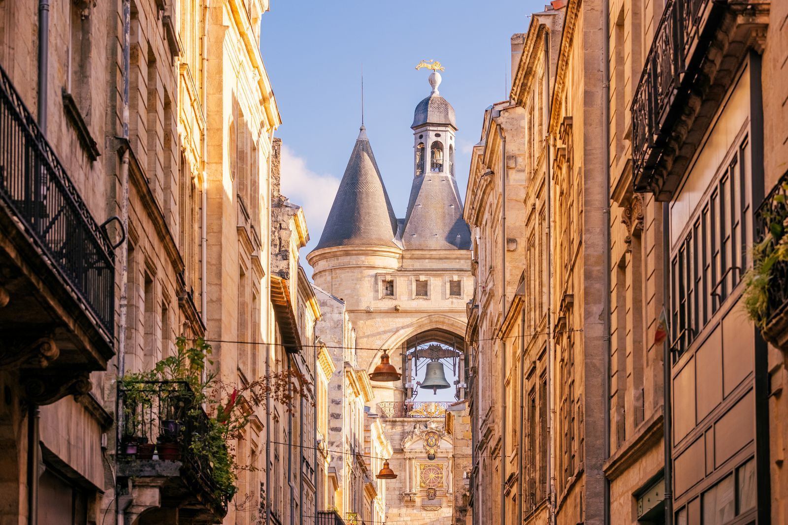 A medieval stone gateway with a large bell tower, known as La Grosse Cloche, in a European city street.