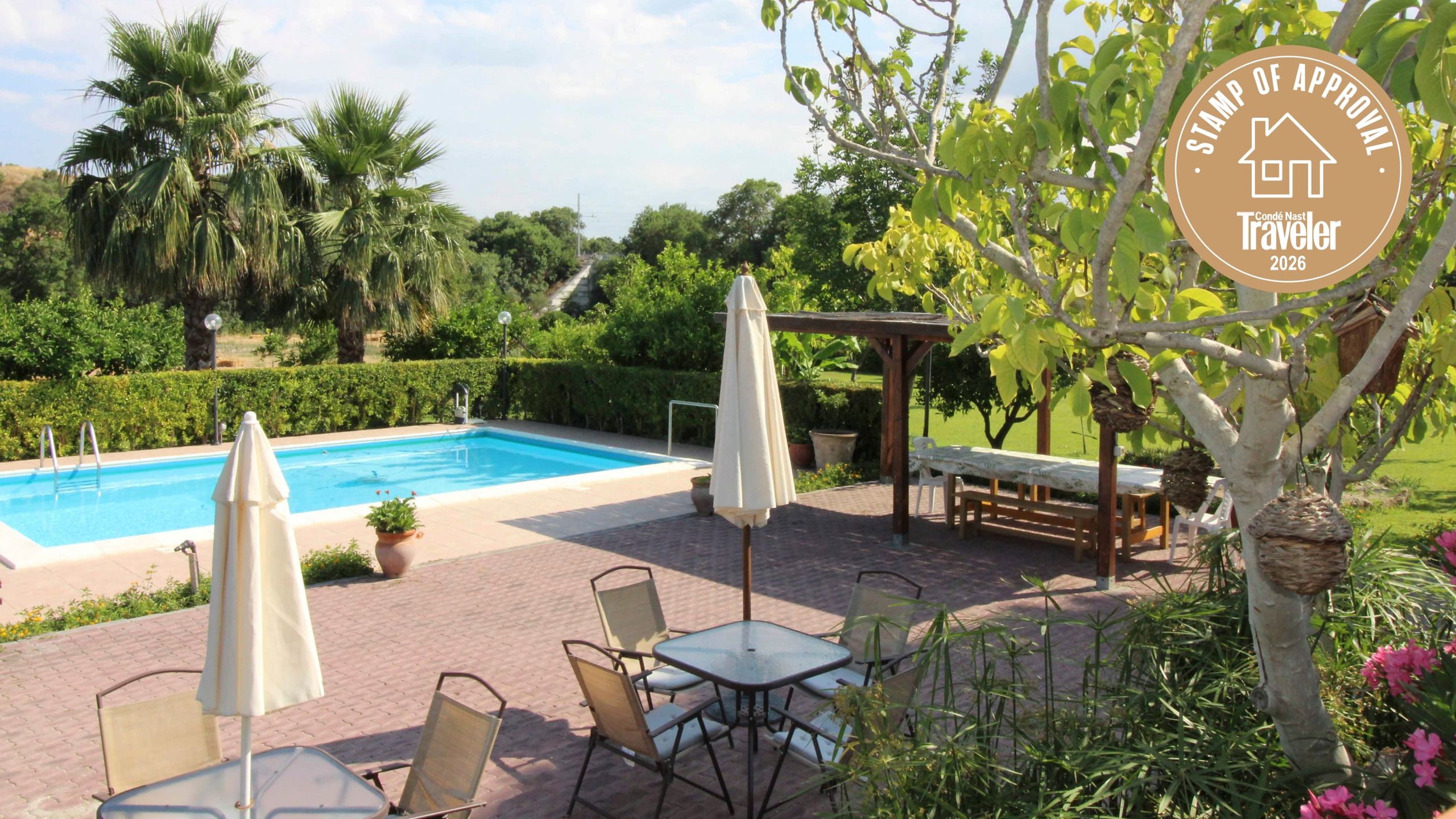 An outdoor dining area at a Sicilian villa with comfortable furniture set against a backyard garden.